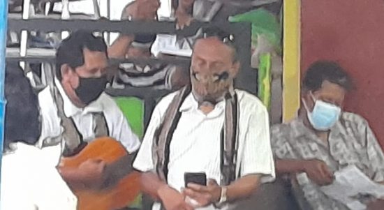 Zet Wadu (pakai masker, kanan) membaca tata ibadah (liturgi) sementara di sisi kirinya jemaat gereja melantunkan kidung penghiburan. ( foto: shitri/ kupangterkini.com)