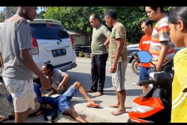 Koban kecelakaan lalulintas yang terjatuh tengah ditolong warga sekitar lokasi kejadian. (foto: yandri/kupangterkini.com)