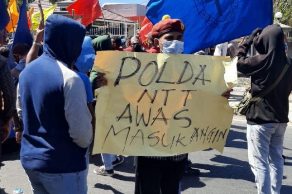 Pendemo saat memegang spanduk bertuliskan polda NTT awas masuk angin. (yandry/kupangterkini.com)