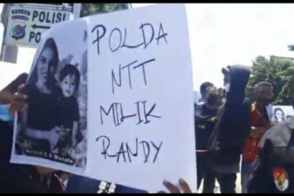 Pendemo membawa poster yang bertuliskan "Polda NTT milik Randy" saat melaksanakan aksi damai di depan Mako Polda NTT